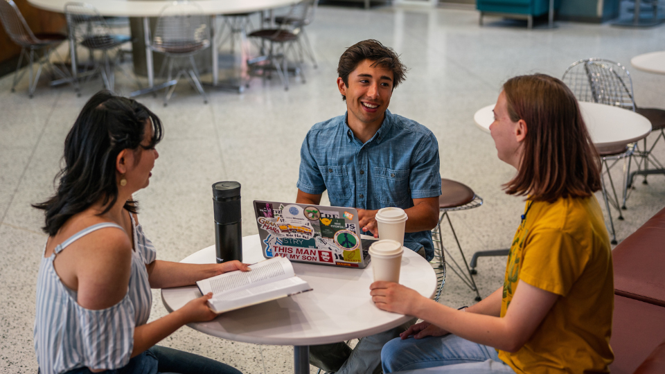 Three UMD students talking and laughing together in a common space on campus